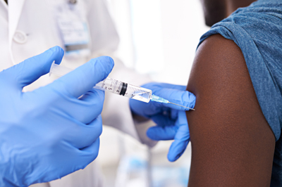 Close-up of a person getting the flu shot in their arm from a health care provider