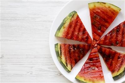 Grilled spicy watermelon slices arranged in a one-layer circle on a white plate