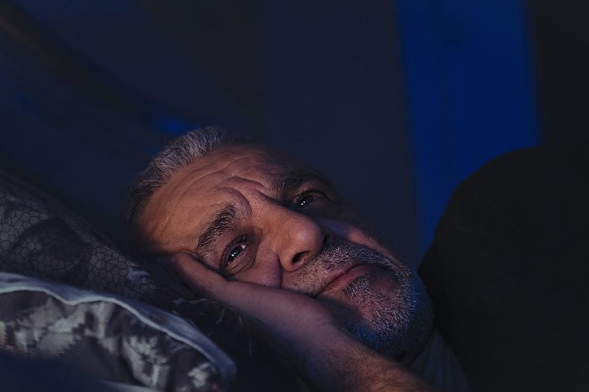 Man laying in bed awake
