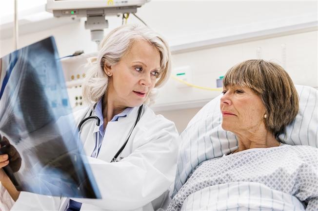 Mature female doctor checking X-ray with mature female patient