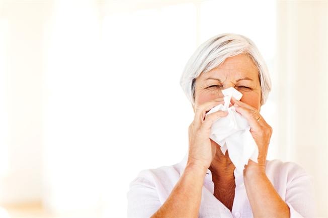 Older woman blowing nose
