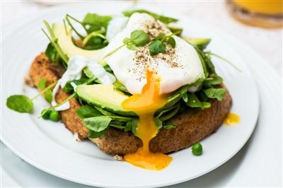 Poached egg, parsley and avocado on toast on a plate