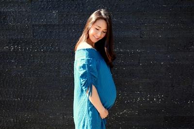 Pregnant woman standing in profile showing off her baby bump