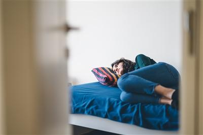 Young adult woman laying on bed alone in room