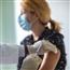 Woman wearing a mask is getting a flu vaccination administered by doctor in a mask