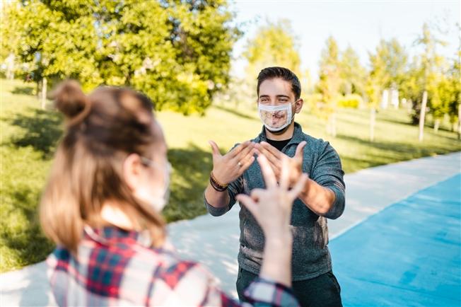 Deaf person communicating using sign language with seethrough mask