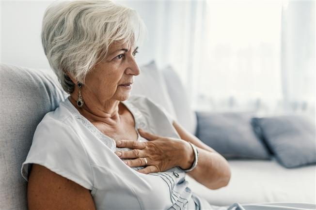Senior woman with hand on chest heart attack symptoms