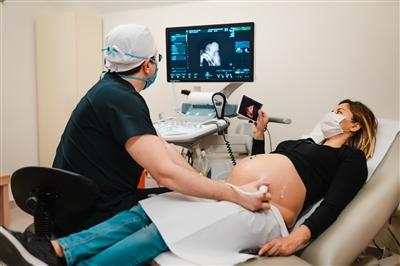Pregnant woman wearing mask and getting ultrasound performed during COVID