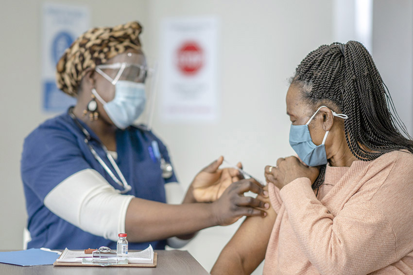 African American nurse giving vaccination to African American woman