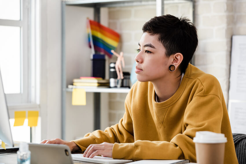Person working at desk with pride flag in the background