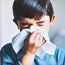Young boy sneezing into a tissue