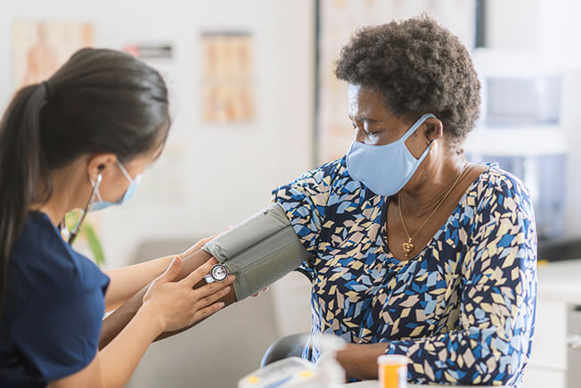 Nurse using a blood pressure gauge to check an elderly woman's health