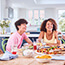 Family sitting around table at home eating meal together 