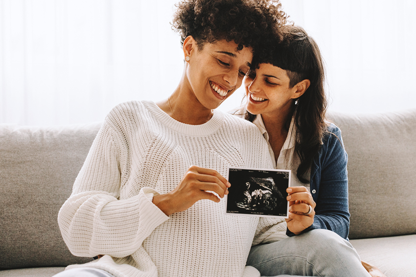 Same-sex pregnant couple holding up their ultrasound scan.