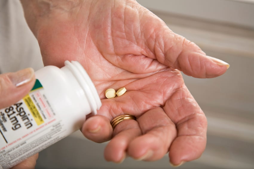 Hand with two aspirin tablets. 