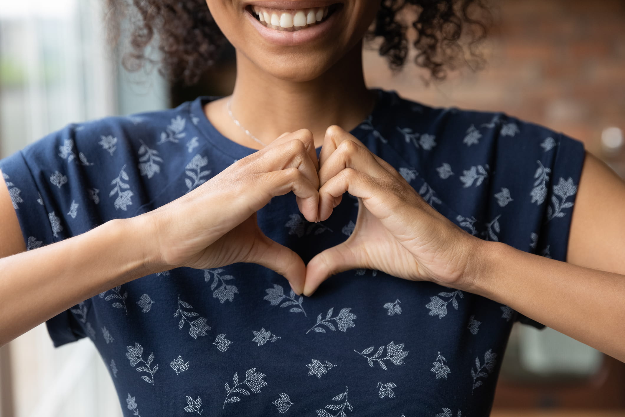 Smiling woman show heart hand gesture