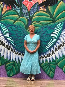 Diane Laskowski standing in front of a wall mural with wings.