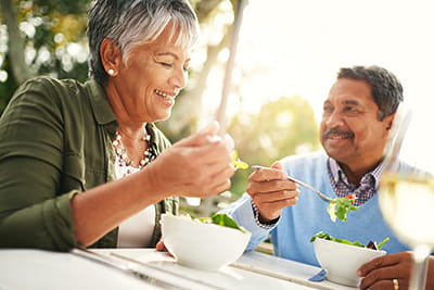 Man and woman enjoying eating salad at outside table