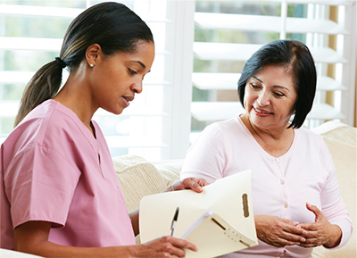 Nurse talking with patient's loved one going over information in a file folder