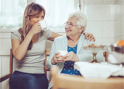 Middle-aged woman and mature woman sitting enjoying a cup of tea, sitting and chatting in a kitchen