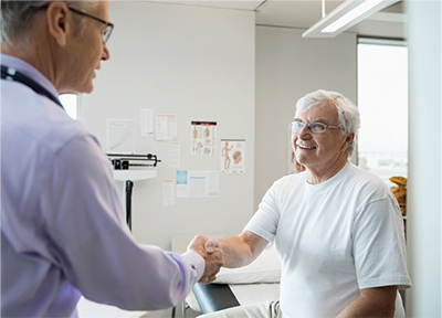 Older male patient shaking hand with health care provider