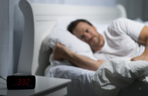 man laying in bed having trouble falling asleep